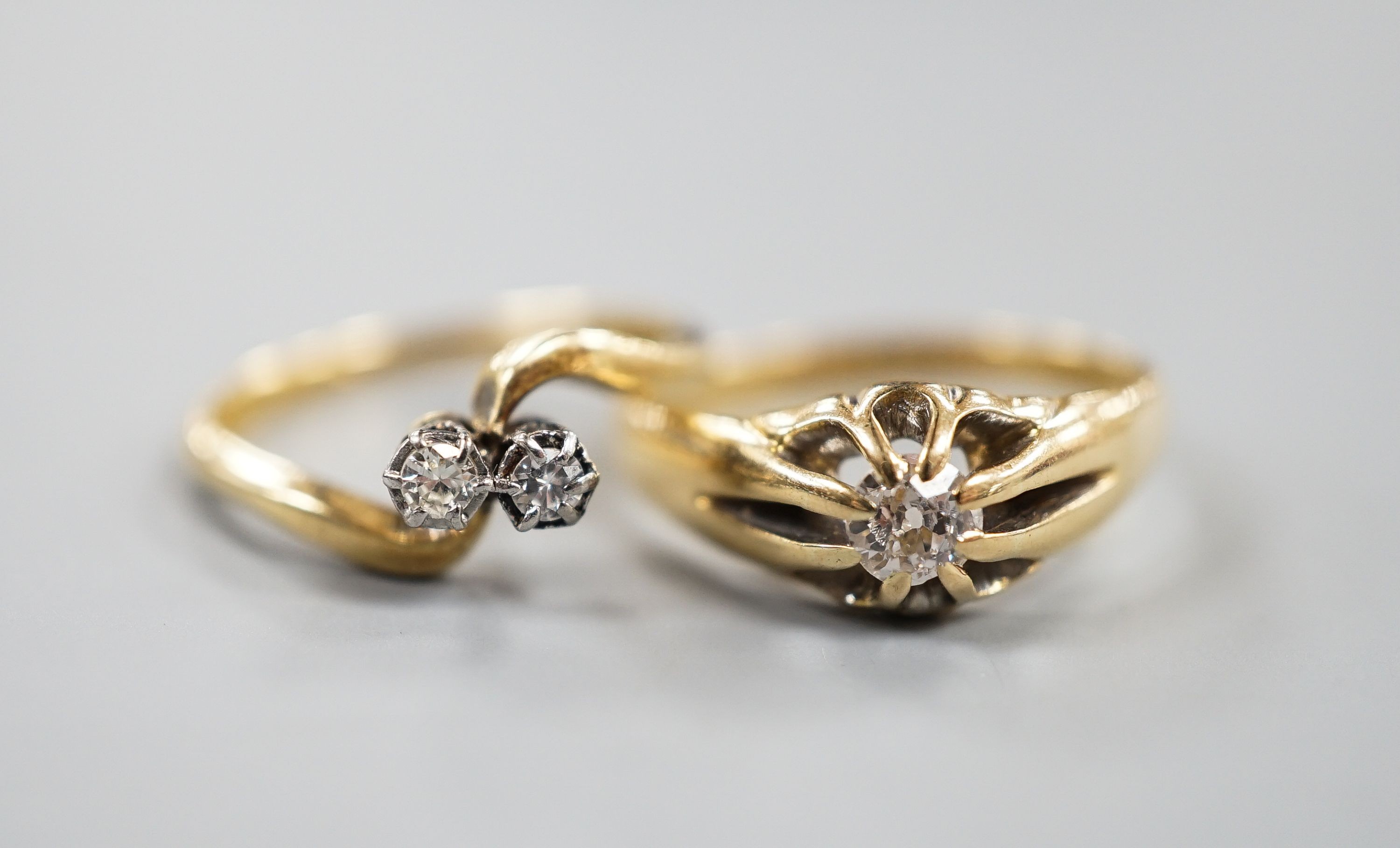 An early 20th century 18ct gold and claw set solitaire diamond ring, size O and an 18ct & Pt, two stone diamond set crossover ring, size K, gross weight 5.7 grams.